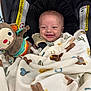 baby, smile, car_seat, blanket, toy, pacifier, monkey_toy, infant, child, happy, face, clothing, cute, sitting, indoor, safety_warning, fabric, head, comfort, blanket_pattern