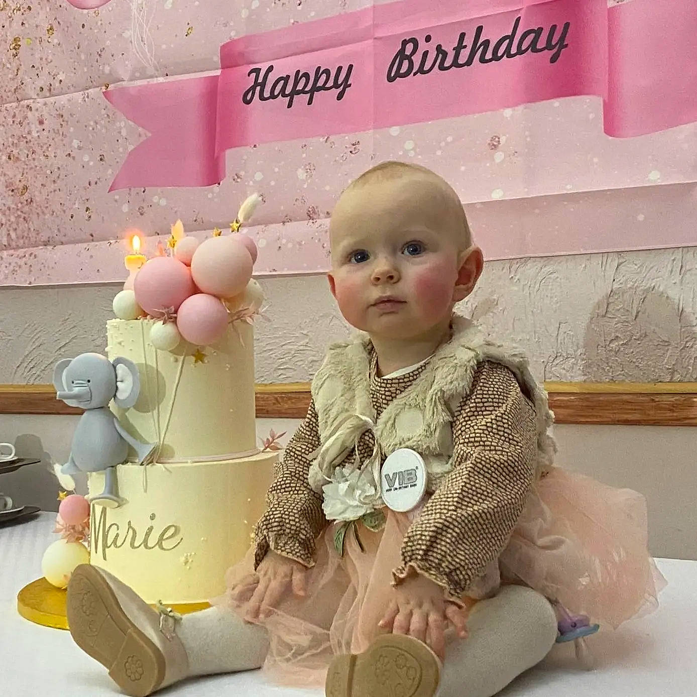 Marie participe au concours pour gagner de l'argent avec cette photo : baby, baby_toddler_clothing, baby_toys, child, font, happy, head, lighting_accessory, paper_product, person, pink, room, sitting, sleeve, toddler, toy, white