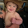 Mikayla is registered to the contest to win money with this photo: baby, child, smiling, hat, cowboy_hat, diaper, tattoo, hand, adult, indoor, person, holding, blue_eyes, skin, face, cheerful, cute, happy, nail_polish, casual