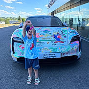 Thyam participe au concours pour gagner de l'argent avec cette photo : child, car, porsche, colorful, drawing, hood, road, building, glass, reflection, sky, clouds, happy, smiling, shorts, sandals, cap, outdoor, daylight, asphalt