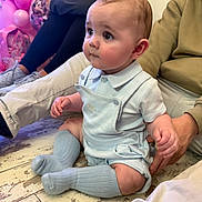 Shae is registered to the contest to win money with this photo: baby, child, infant, floor, socks, overalls, person, adult, balloons, pink, party, seated, wood_floor, clothing, cute, indoor, people, hand, face, portrait