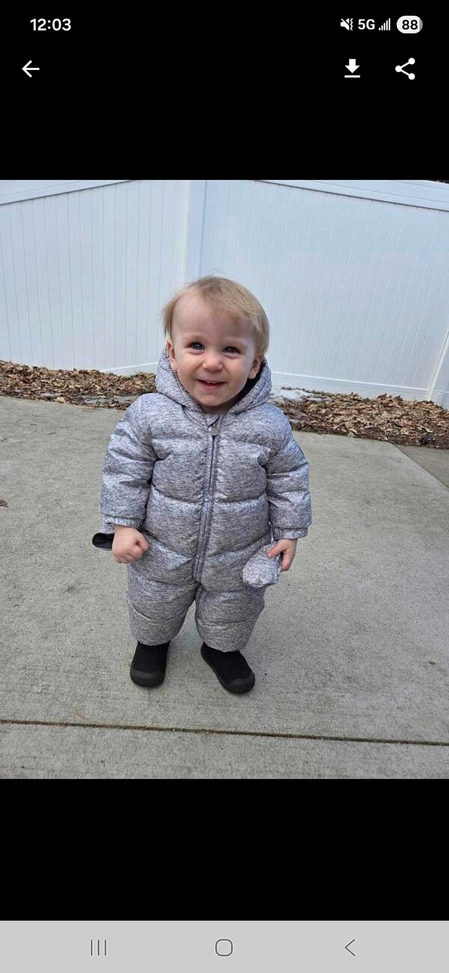 Cory joined the competition — help win amazing prizes! child, toddler, baby, smile, snowsuit, puffy_coat, hood, boots, standing, concrete, sidewalk, fence, outdoor, cold_weather, leaves, portrait, front_view, happy, candid, person