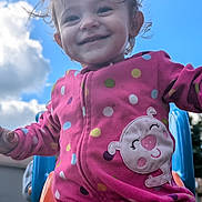 Addilyn is registered to the contest to win money with this photo: toddler, child, smiling, playground, slide, onesie, polka_dot, outdoor, sky, clouds, happy, cute, fun, play, colorful, baby, joy, face, clothing, daytime