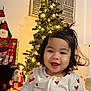 Kelyana participe au concours pour gagner de l'argent avec cette photo : toddler, child, smiling, christmas_tree, holiday_decorations, lights, indoor, festive, pajamas, heart_pattern, santa_figurine, gift_bag, curly_hair, joyful, warm_lighting, celebration, decoration, person, happy, home
