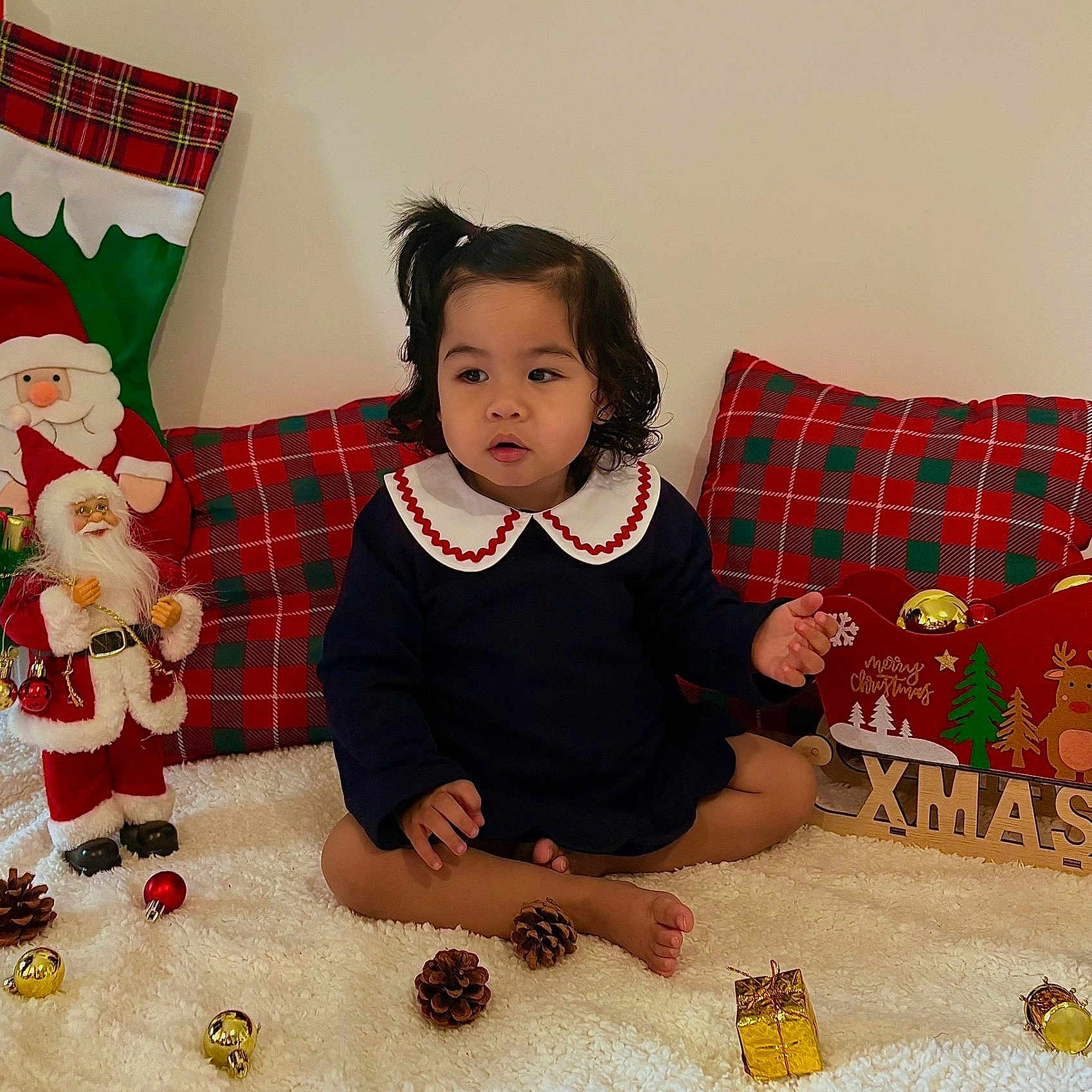 Kelyana participe au concours pour gagner de l'argent avec cette photo : baubles, carpet, child, christmas, curly_hair, cute, decorations, festive, holiday, indoor, navy_dress, pillow, pinecones, plaid, santa_claus, sleigh, toddler, toy, white_collar, xmas