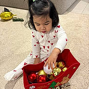 Kelyana participe au concours pour gagner de l'argent avec cette photo : toddler, child, pajamas, heart_pattern, christmas, ornaments, red_sleigh, carpet, indoor, holiday, decorations, playful, festive, toy, floor, person, cute, young_child, home, seasonal