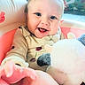 baby, child, infant, smiling, happy, portrait, face, eyes, blond_hair, plush_toy, stuffed_animal, playroom, indoor, seated, clothing, sweater, toy, colorful, close_up, joyful