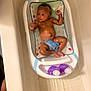 Skylan is registered to the contest to win money with this photo: baby, baby_bath_seat, bath_time, bathroom, bathtub, blue_cloth, bottle, child, cleaning, curious, home, infant, purple, relaxed, safety_seat, shampoo, skin, toddler, wash, water