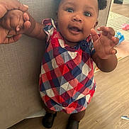 Unique is registered to the contest to win money with this photo: toddler, child, baby, hand_holding, dress, pigtails, smiling, standing, indoor, floor, furniture, person, home, curly_hair, shoes, checkered_pattern, cute, happy, portrait, reaching
