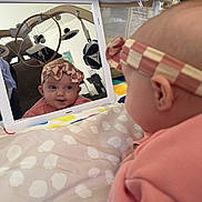 Mia joined the competition — help win amazing prizes! baby, baby_toys, blanket, child, closeup, curious, cuteness, expression, face, gaze, headband, indoor, infant, mirror, person, pink_clothing, playful, reflection, soft, tablet