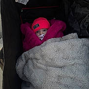 Mia is registered to the contest to win money with this photo: baby, stroller, blanket, beanie, pacifier, fuzzy_jacket, child, cozy, cold_weather, warm_clothing, infant, wrapped_up, cute, face, portrait, outdoor, bundle, pink, gray, soft_texture