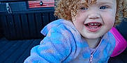Isabella joined the competition — help win amazing prizes! child, toddler, curly_hair, blue_eyes, onesie, pastel_colors, smiling, outdoor, pickup_truck, vehicle, playful, happy, face, person, daylight, clothing, baby, reaching, cute, fun