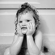 Isabella is registered to the contest to win money with this photo: child, toddler, bath, water, bubbles, wet_hair, curly_hair, smile, face, hands, black_and_white, portrait, cute, playful, indoors, skin, expression, young_child, sitting, bathtub