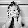 child, toddler, bath, water, bubbles, wet_hair, curly_hair, smile, face, hands, black_and_white, portrait, cute, playful, indoors, skin, expression, young_child, sitting, bathtub