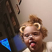 Isabella joined the competition — help win amazing prizes! child, curly_hair, tongue_out, glasses_filter, bear_ears_filter, indoor, wall_art, light, playful, portrait, tshirt, cute, fun, face, person, expression, young_child, happy, home, digital_filter