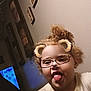 child, curly_hair, tongue_out, glasses_filter, bear_ears_filter, indoor, wall_art, light, playful, portrait, tshirt, cute, fun, face, person, expression, young_child, happy, home, digital_filter