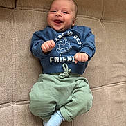 Jules participe au concours pour gagner de l'argent avec cette photo : baby, infant, smiling, blue_sweatshirt, green_pants, sock, couch, furniture, happy, face, person, child, clothing, indoors, cute, playful, young, sitting, cozy, portrait