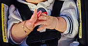 Neda is registered to the contest to win money with this photo: baby, infant, child, car_seat,  자동차, harness, buckled, sitting, face, eyes, hands, clothing, white_shirt, pants, portrait, indoors, vehicle, safety, wide_eyed, adorable