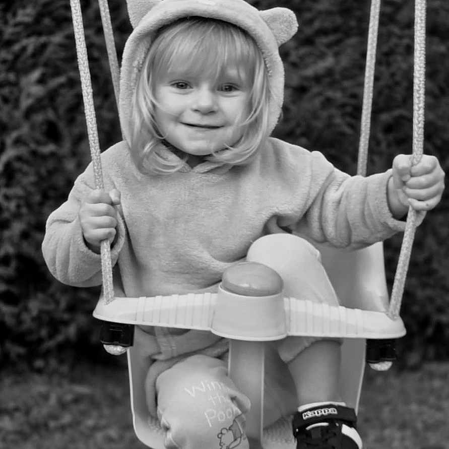 Meysie a rejoint le concours — aidez-le/la à gagner de superbes lots ! black_and_white, child, clothing, cute, fun, grass, happy, hoodie, nature, outdoor, person, play, playground, portrait, rope, seat, shoes, smile, swing, toddler