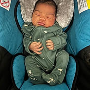 Ace joined the competition — help win amazing prizes! newborn, baby, sleeping, car_seat, green_onesie, infant, headrest, cushion, warning_label, child, peaceful, cute, small_hands, soft_fabric, indoor, portrait, resting, cozy, child_safety, blue_cushion