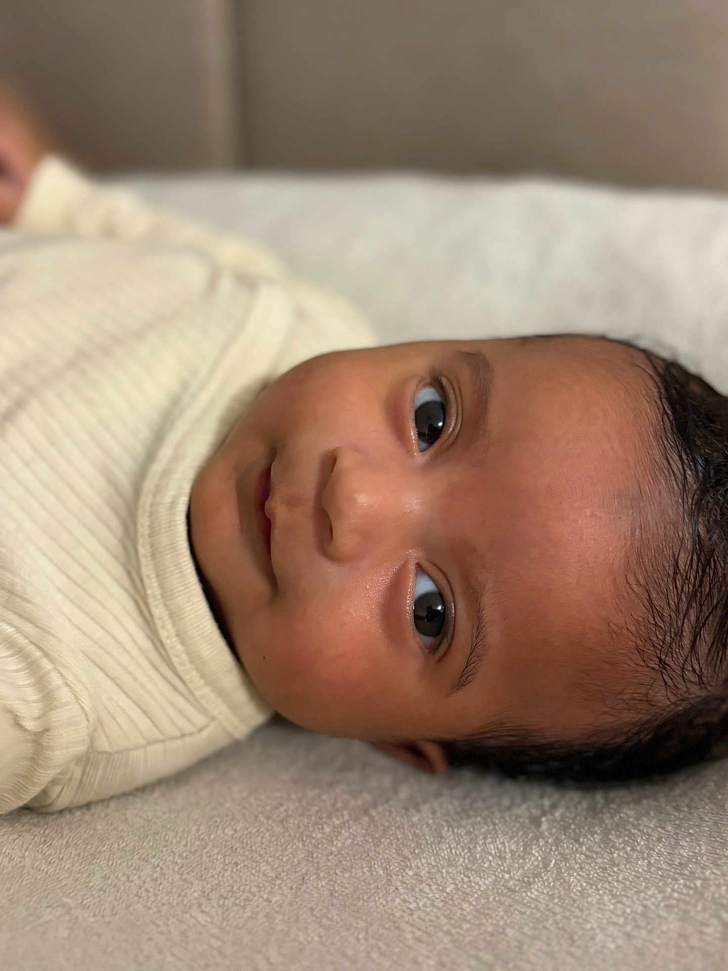 Nohé participe au concours pour gagner de l'argent avec cette photo : baby, infant, face, skin, eyes, clothing, ribbed, cream, lying_down, soft_surface, portrait, close_up, child, cute, young, person, indoors, cozy, head, expression