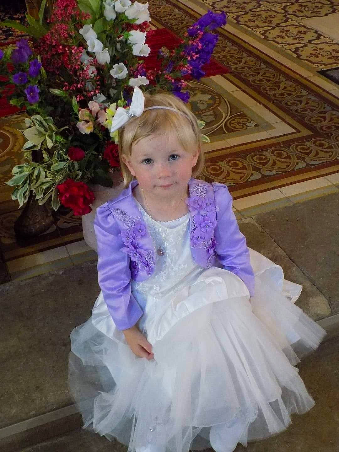 Talya participe au concours pour gagner de l'argent avec cette photo : baby_toddler_clothing, bouquet, bridal_accessory, dress, embellishment, event, eye, flower, flower_arranging, happy, human_body, iris, magenta, person, petal, pink, plant, purple, smile, toddler