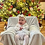 baby, blanket, chair, christmas, christmasdecorations, clothing, face, festival, furniture, happy, head, hosiery, lighting, person, photography, plant, portrait, smile, sock, tree