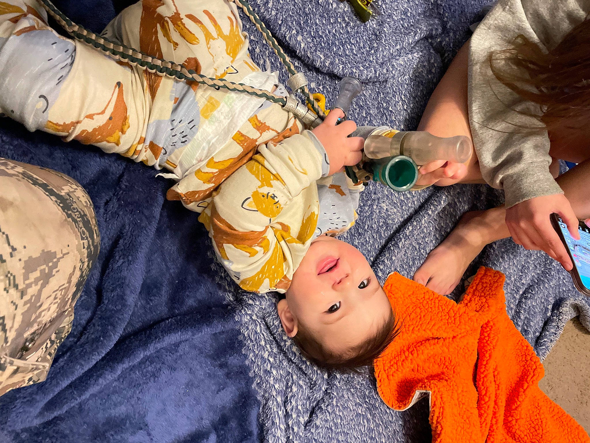 Kaiden is registered to the contest to win money with this photo: arm, baby, baby_products, baby_toddler_clothing, child, comfort, finger, fun, gesture, hand, linens, nail, orange, pattern, person, room, sitting, sleeve, textile, toddler
