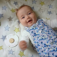 Roxane participe au concours pour gagner de l'argent avec cette photo : baby, infant, smiling, face, hand, blanket, stars, pattern, blue, white, floral, clothing, buttons, plaque, milestone, lying_down, happy, cute, young_child, portrait