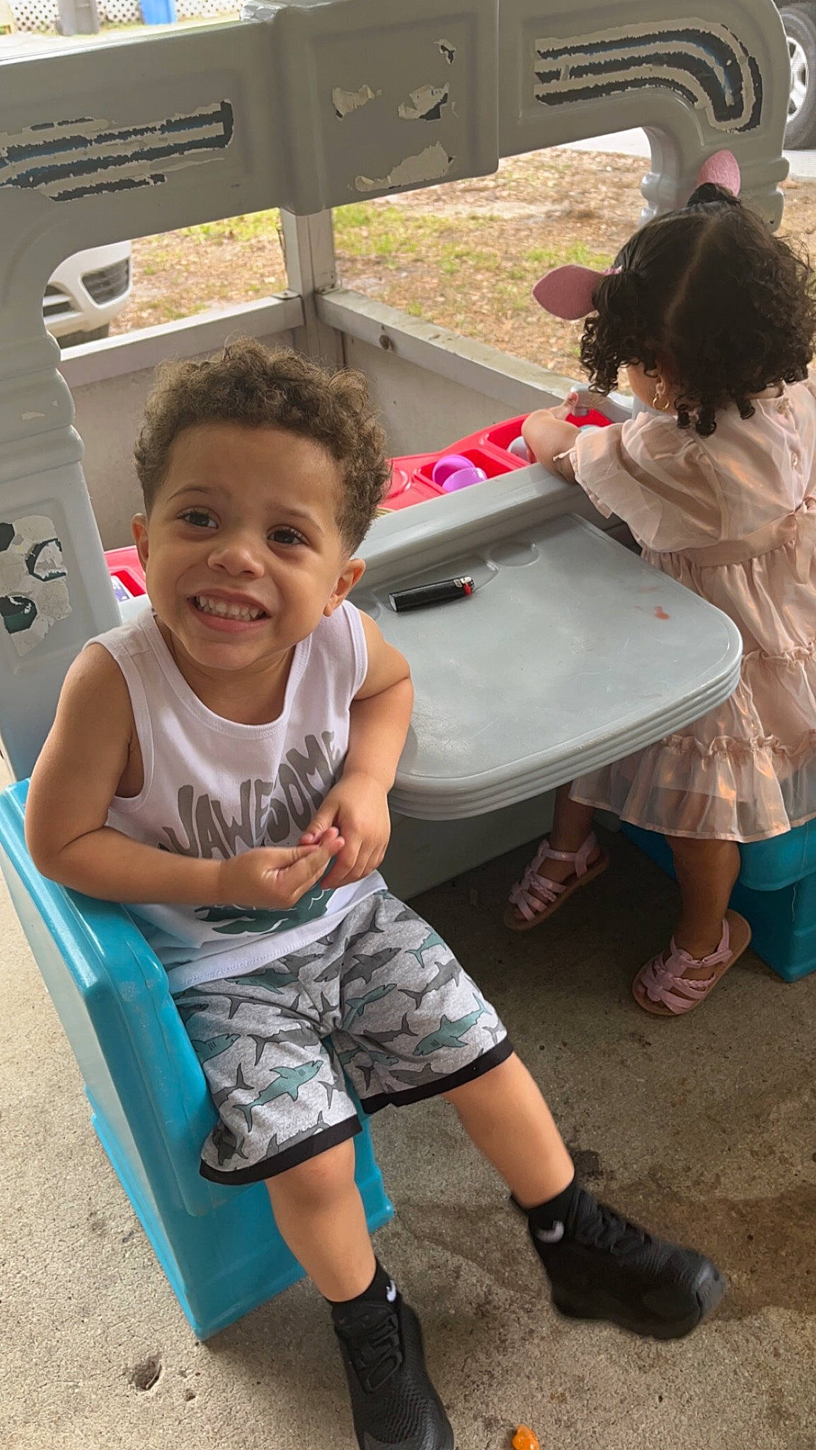 Dakari is registered to the contest to win money with this photo: bench, child, event, flip_flops, fun, happy, human_leg, joy, leg, leisure, person, pink, recreation, sandal, shorts, sitting, slipper, smile, t_shirt, toddler