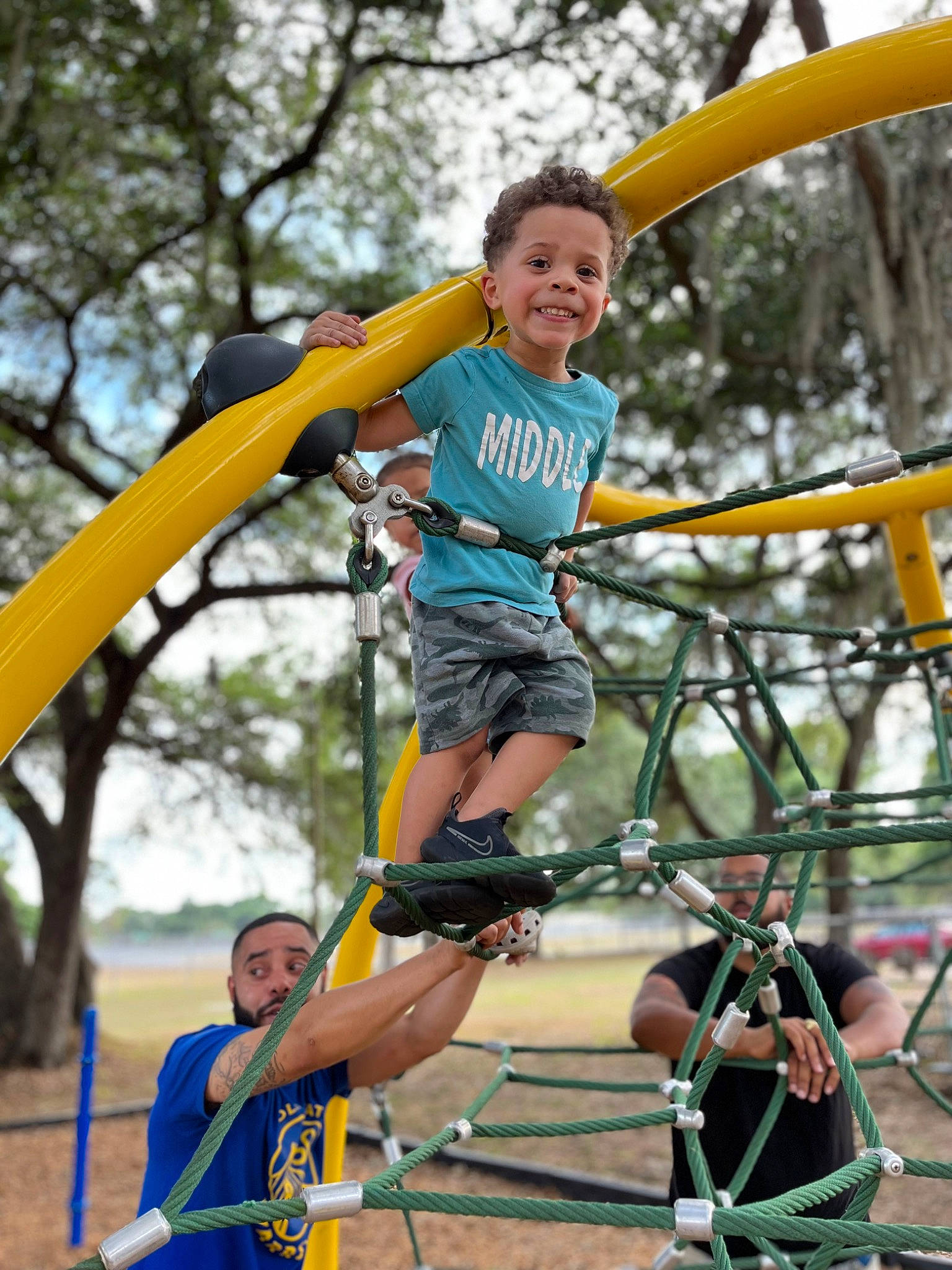 Dakari is registered to the contest to win money with this photo: city, clothing, entertainment, event, fun, happy, joy, leisure, outdoor_play_equipment, outdoor_recreation, person, plant, playground, pole, recreation, shorts, smile, summer, swing, t_shirt