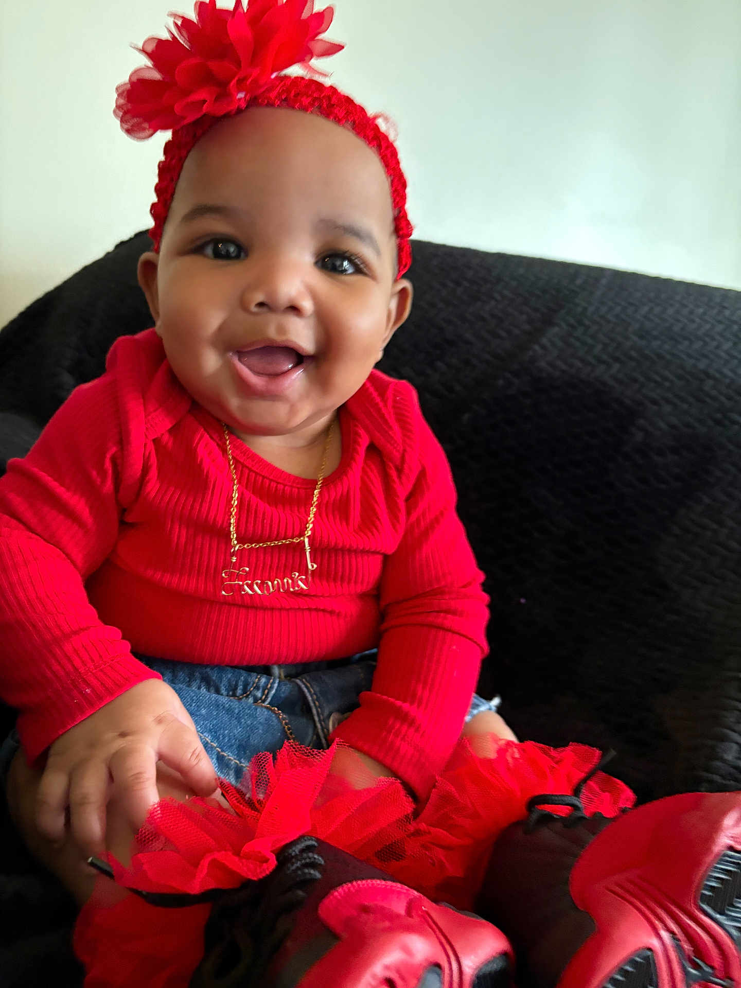 Leeonnie joined the competition — help win amazing prizes! baby, child, smiling, red_clothing, headband, flower, tutu, shoes, jeans, happy, sitting, indoors, cute, portrait, face, hand, couch, black_background, accessory, gold_necklace