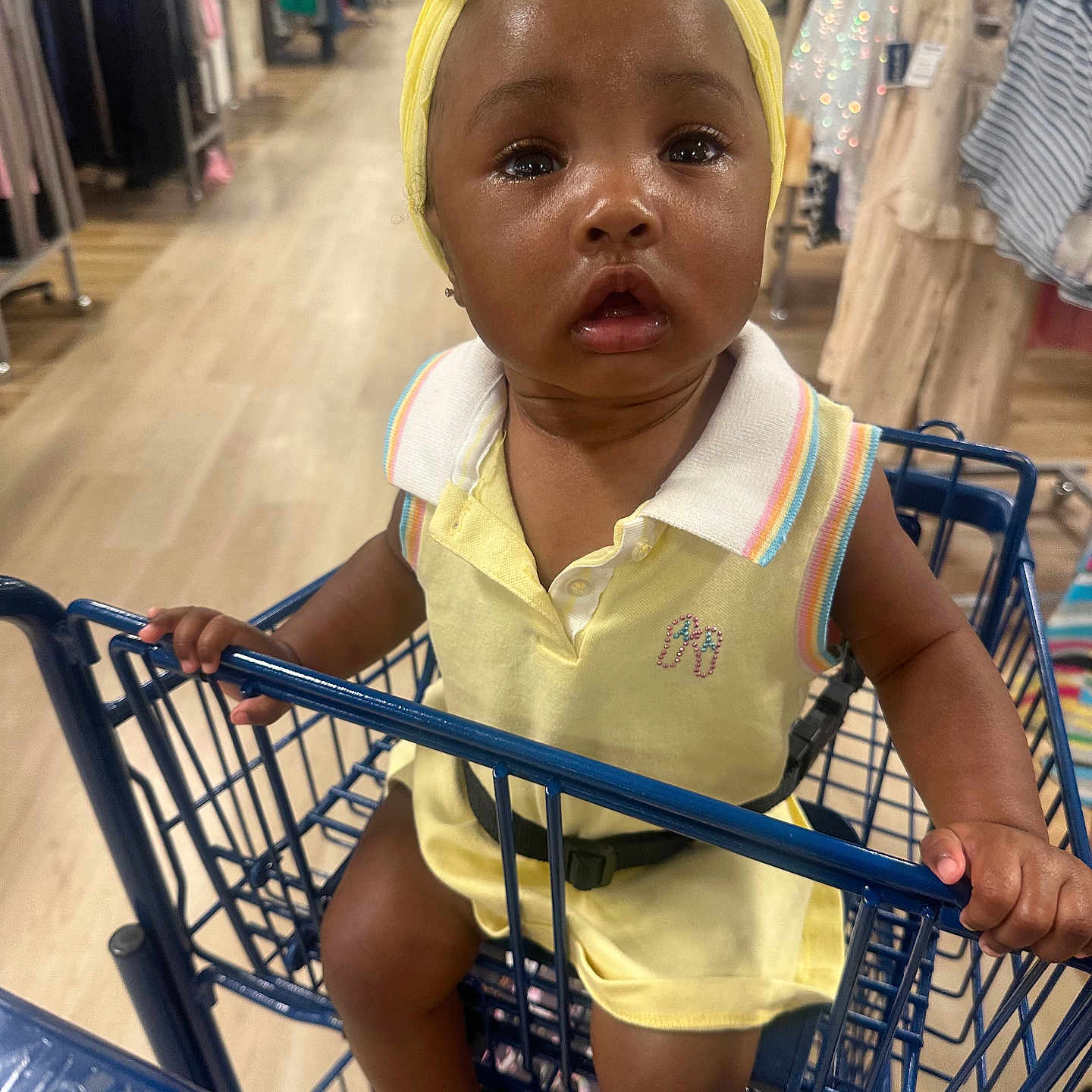 Levyn joined the competition — help win amazing prizes! toddler, child, shopping_cart, yellow_headband, yellow_outfit, clothing_store, aisle, curious, baby, infant, person, shopping, retail, colorful_clothes, floor, hand, seatbelt, bright_colors, indoor, portrait