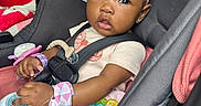 Levyn joined the competition — help win amazing prizes! baby, child, car_seat, headband, toy, bottle, infant, seatbelt, pink, clothing, cute, portrait, car_interior, person, young_child, accessory, closeup, sitting, holding, expression