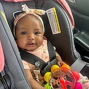 Levyn is registered to the contest to win money with this photo: baby, child, car_seat, toy, headband, seatbelt, infant, cute, smiling, colorful, floral, clothing, car_interior, safety, young_child, portrait, happy, person, indoors, baby_girl
