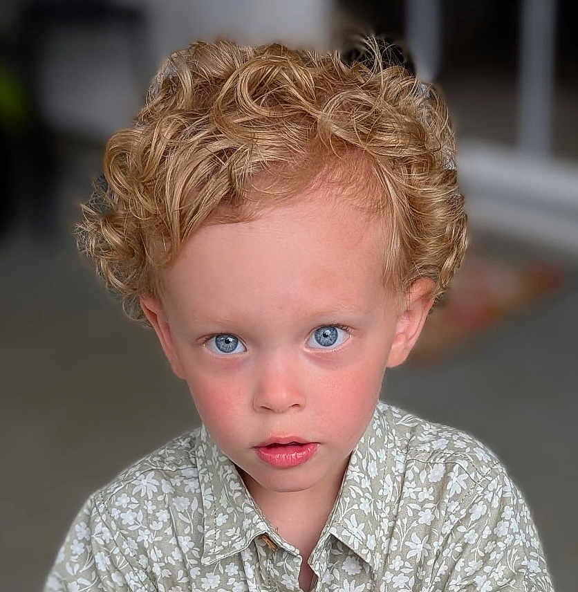 Milo is registered to the contest to win money with this photo: child, boy, curly_hair, blonde, blue_eyes, portrait, close_up, shirt, floral_pattern, face, young, looking, indoor, soft_light, skin, expression, cute, innocent, childhood, person