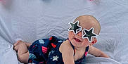 Briella is registered to the contest to win money with this photo: baby, sunglasses, star_shaped_glasses, bunting, red_white_blue, outdoor, summer, infant, smiling, white_sheet, cute, playful, cape, headwear, person, child, portrait, holiday, fun, casual