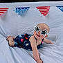 baby, sunglasses, star_shaped_glasses, bunting, red_white_blue, outdoor, summer, infant, smiling, white_sheet, cute, playful, cape, headwear, person, child, portrait, holiday, fun, casual