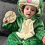 baby, infant, child, frog_costume, green_costume, hood, milestone_sign, wooden_disc, eight_months, sofa, textured_sofa, plush, portrait, sitting, hand, eyes, mouth_open, cute, home_interior, photography