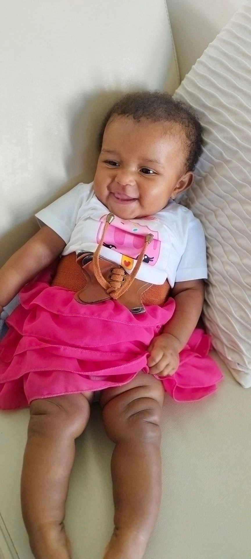 Janilia Magui a rejoint le concours — aidez-le/la à gagner de superbes lots ! baby, child, clothing, comfort, couch, cute, face, hand, happy, home, indoor, infant, legs, pink_skirt, portrait, seated, skin, smiling, toddler, white_shirt