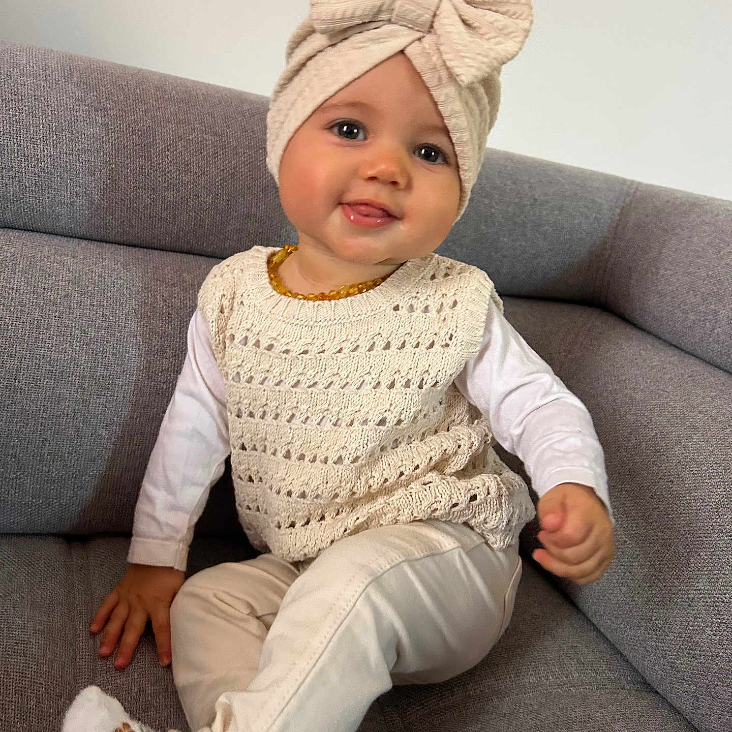 Inaya a rejoint le concours — aidez-le/la à gagner de superbes lots ! baby, bow, child, couch, cozy, cream_clothing, cute, face, furniture, happy, indoors, knitted_hat, long_sleeve_shirt, pants, portrait, sitting, smiling, socks, toddler, young_child