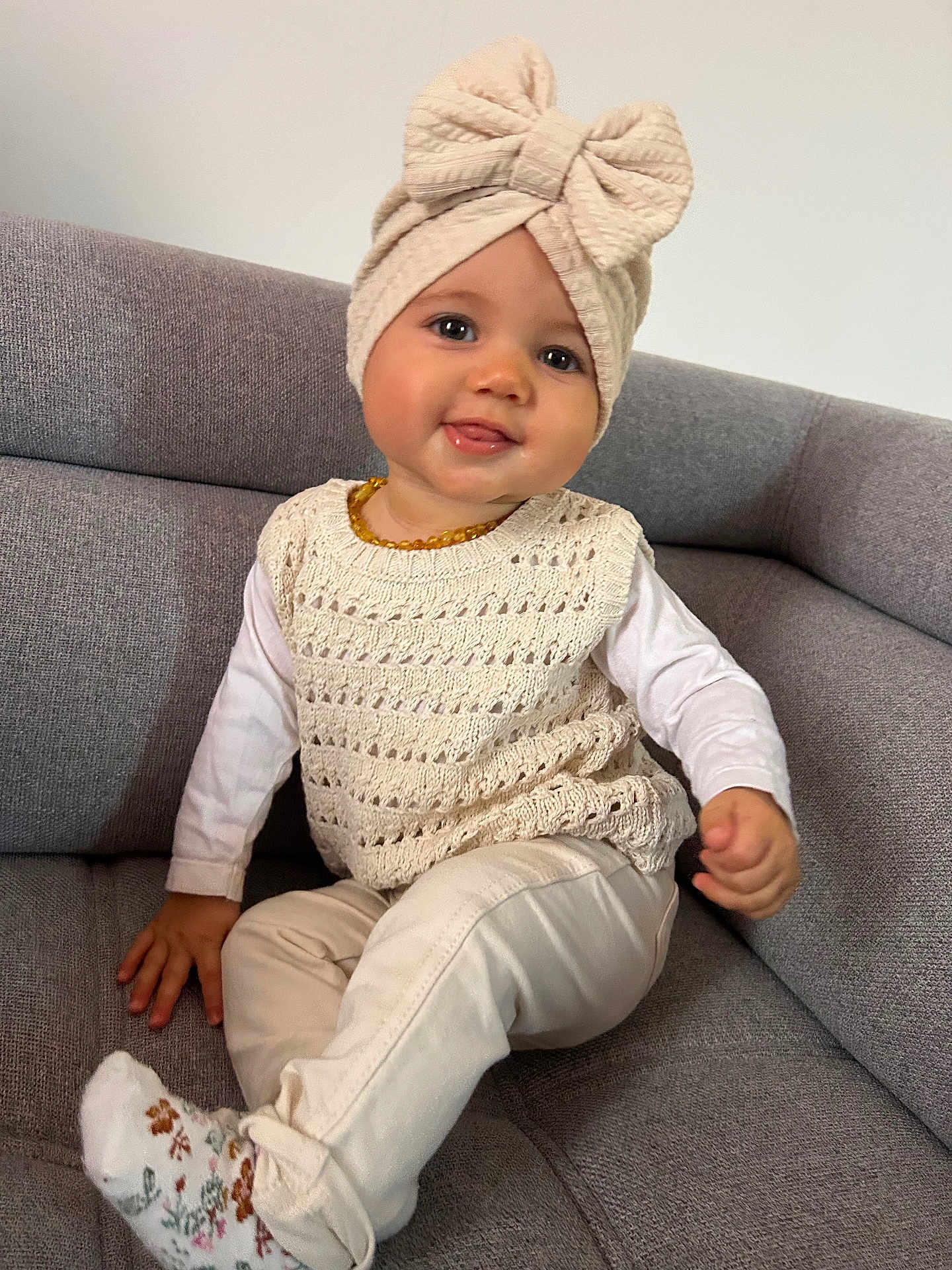 Inaya a rejoint le concours — aidez-le/la à gagner de superbes lots ! toddler, child, baby, smiling, sitting, couch, knitted_hat, bow, cream_clothing, long_sleeve_shirt, pants, socks, face, happy, indoors, furniture, portrait, cute, young_child, cozy