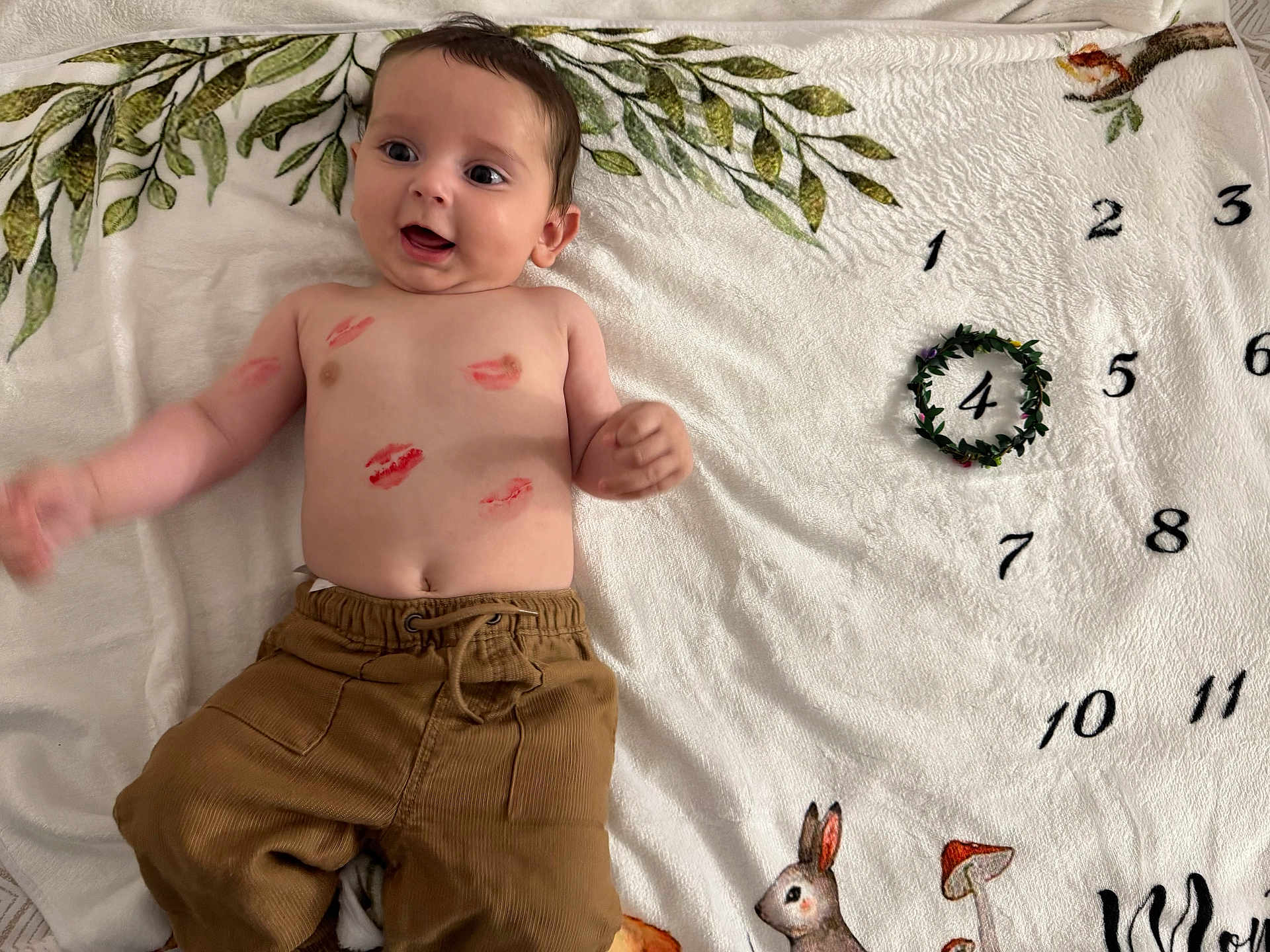 Alex participe au concours pour gagner de l'argent avec cette photo : baby, blanket, child, decorative, face, greenery, hand, happy, indoors, infant, kiss_marks, lying_down, mushroom, numbers, pants, playful, rabbit, skin, smiling, woodland_animals