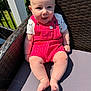 baby, child, smiling, outdoor, sunlight, red_overalls, white_shirt, star_pattern, chair, woven_chair, legs, feet, happy, cute, infant, summer, nature, greenery, portrait, seat