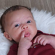 Jasiah joined the competition — help win amazing prizes! baby, infant, face, hand, finger, nose, maroon_clothing, fluffy_blanket, curious_expression, lying_down, close_up, skin, person, newborn, indoor, portrait, cute, small_hands, head, eyes