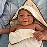 Makari joined the competition — help win amazing prizes! baby, towel, hooded_towel, smiling, face, infant, bed, blanket, skin, hand, cute, child, lying_down, blue_eyes, soft_texture, person, indoors, sleepwear, cozy, comfort