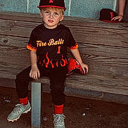 Ridge is registered to the contest to win money with this photo: child, baseball, bench, black_uniform, red_glove, cap, concrete_wall, dirt, sports, young_player, cleats, team_uniform, sitting, glove, outdoor, kid, face, sport_equipment, hat, fire_design