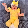 baby, child, yellow_clothing, headband, bow, smiling, happy, sitting, couch, gray_couch, plush, indoor, portrait, cute, infant, person, toddler, baby_girl, closeup, fabric