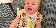 Marliya-Mae is registered to the contest to win money with this photo: baby, child, smiling, sitting, couch, green_bow, colorful_clothing, floral_pattern, pink_blanket, home_interior, happy, cute, infant, portrait, indoors, person, furniture, cozy, bright, young_child