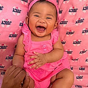 Princess is registered to the contest to win money with this photo: baby, child, smiling, laughing, pink_clothing, headband, hand, adult_hand, sitting, cute, happy, portrait, indoors, fabric, pattern, human, skin, infant, joy, playful